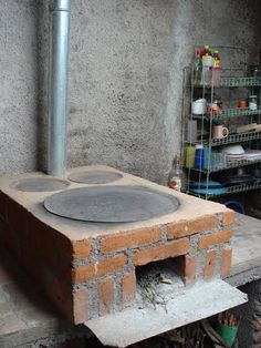 a brick oven sitting on top of a cement block in a room with concrete walls