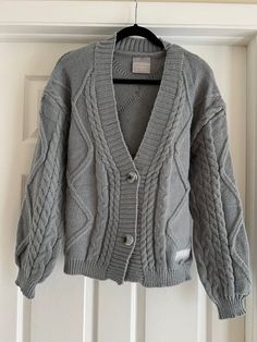 a gray cardigan sweater hanging on a white door with a hanger in front of it