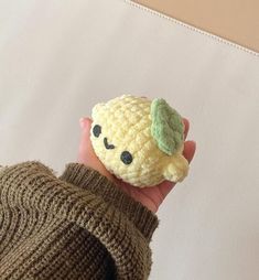 a hand holding a small crocheted lemon