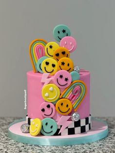 a pink cake decorated with smiley faces and hair clips on top of a countertop