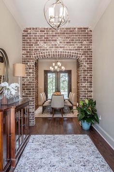 a dining room with a brick wall and wooden flooring that has a rug on it