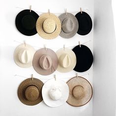 several hats hanging on a wall with clothes pins