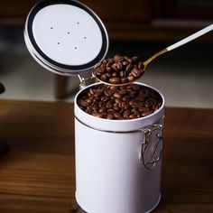 a white container filled with coffee beans on top of a wooden table