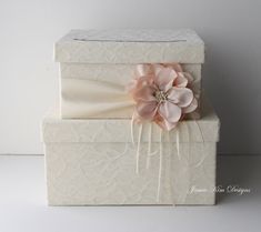 a white box with a pink flower on the top and a bow tie around it