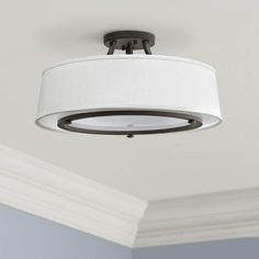 a ceiling light with a white shade hanging from it's center fixture in a room