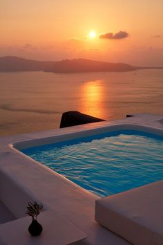 the sun is setting over an ocean with a hot tub in it's foreground