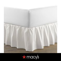 white bed skirt with ruffles on the bottom and bottom, in front of a wooden floor