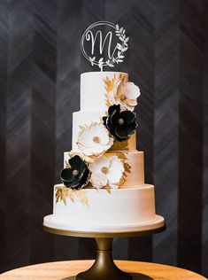 a three tiered wedding cake with black and white flowers on it's side