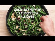 green beans with cranberries and almonds in a skillet on a wooden table