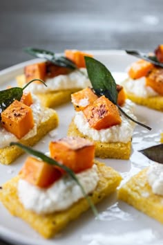 small pieces of food on a white plate with green garnish and some leaves