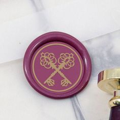 a purple wax seal sitting on top of a piece of paper next to a wooden handle