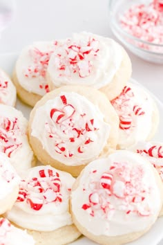 several cookies with white frosting and red sprinkles are on a plate