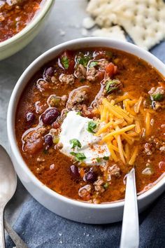 two bowls of chili with cheese and sour cream