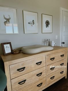 a dresser with drawers and pictures on the wall