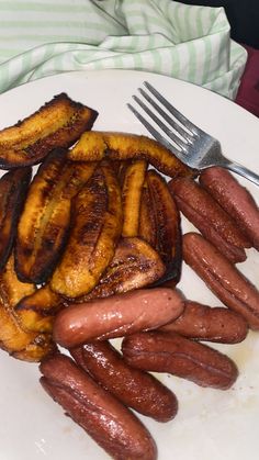 there is a white plate with grilled bananas and sausages next to a fork