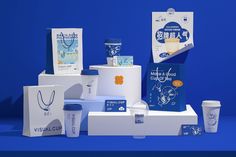 several different items are displayed on a blue display stand with white paper bags and coffee cups