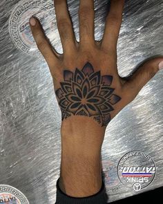 a person's hand with a flower tattoo on the middle of their left hand