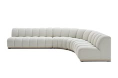 a white sectional couch sitting on top of a wooden floor next to a white wall