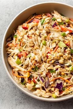 a bowl filled with coleslaw and carrots on top of a white table