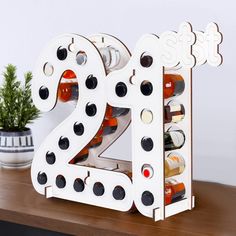 a wooden table topped with a bottle holder filled with wine bottles and numbers that spell out the number twenty