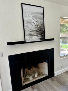 an empty fireplace in a living room with a painting on the mantel above it