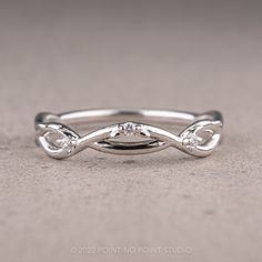 a white gold ring with three diamonds on the top and bottom, sitting on a gray surface