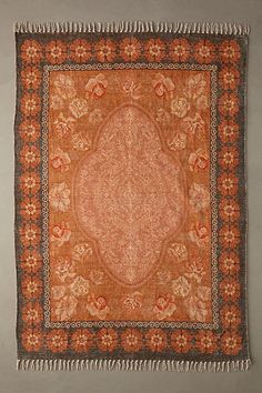 an orange and brown rug hanging on a wall