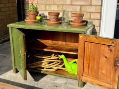 an old wooden cabinet with pots and plants on top