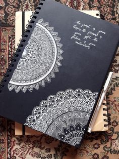 a notebook with an intricate design on the front and back cover sitting on top of a rug