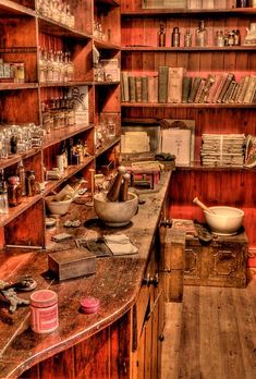 an old fashioned kitchen with lots of books on the shelves and other items in it