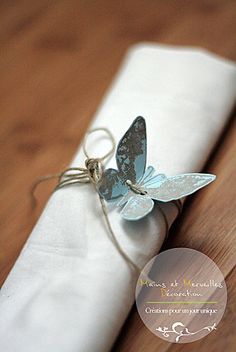 a blue butterfly sitting on top of a white napkin with a string tied to it