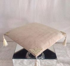 a decorative pillow with tassels on it sitting on a white furnishing