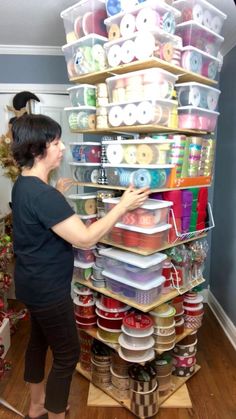 a woman standing next to a stack of plastic containers on top of a wooden floor