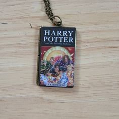 a harry potter book cover pendant on a wooden table with a chain attached to it