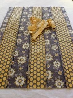 a yellow and gray table runner with polka dots on it, tied to a white table cloth