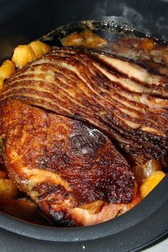 a close up of food in a crock pot with meat and potatoes on the side