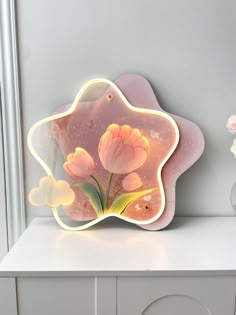 a pink flower shaped light sitting on top of a white counter next to a vase with flowers