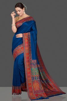 Shop beautiful indigo blue silk saree online in USA with red Kani embroidery border. Get ready for festive occasions and weddings in tasteful designer sarees, Banarasi sarees, handwoven sarees from Pure Elegance Indian clothing store in USA.-full view Blue Kalamkari Pre-draped Saree For Diwali, Blue Katan Silk Saree With Kalamkari Print, Blue Saree With Printed Border, Blue Semi-stitched Saree With Printed Border, Blue Unstitched Saree With Printed Border, Semi-stitched Blue Saree With Printed Border, Blue Pre-draped Saree With Printed Border, Blue Kalamkari Print Blouse For Wedding, Blue Silk Traditional Wear With Printed Border