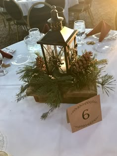 the table is set with pine cones, evergreens and candlesticks for an elegant centerpiece