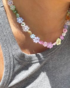 a close up of a person wearing a necklace with colorful flowers on it's neck