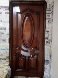 a large wooden door in front of a wall with newspaper on it's side