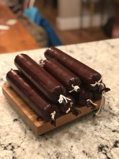 four chocolate covered hot dogs on a cutting board