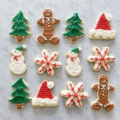 cookies decorated like christmas trees, snowmen and santa hats are displayed on a table