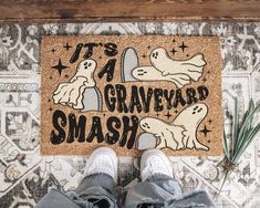 someone standing in front of a door mat that says it's a graveyard smash