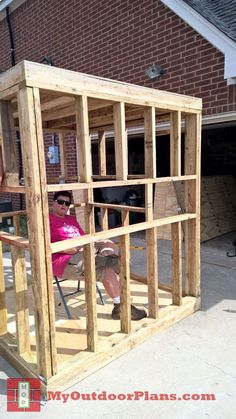 a woman sitting in a chair on top of a wooden structure with the door open