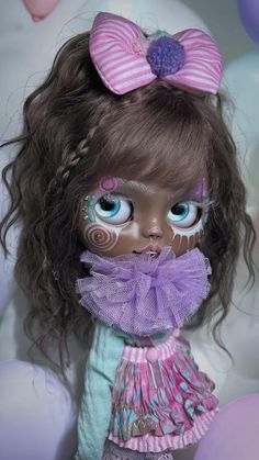 a close up of a doll with blue eyes and brown hair wearing a purple dress