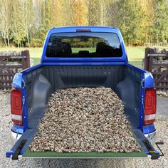 the back end of a blue pick up truck with gravel in it's bed