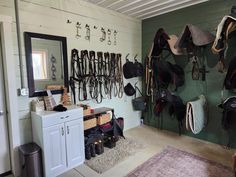 a room filled with lots of horse tacks and saddles hanging on the wall