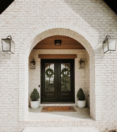 the front entrance to a house with two potted plants on either side of the door