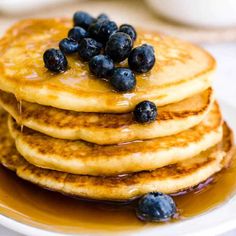 a stack of pancakes with blueberries and syrup on top are sitting on a plate